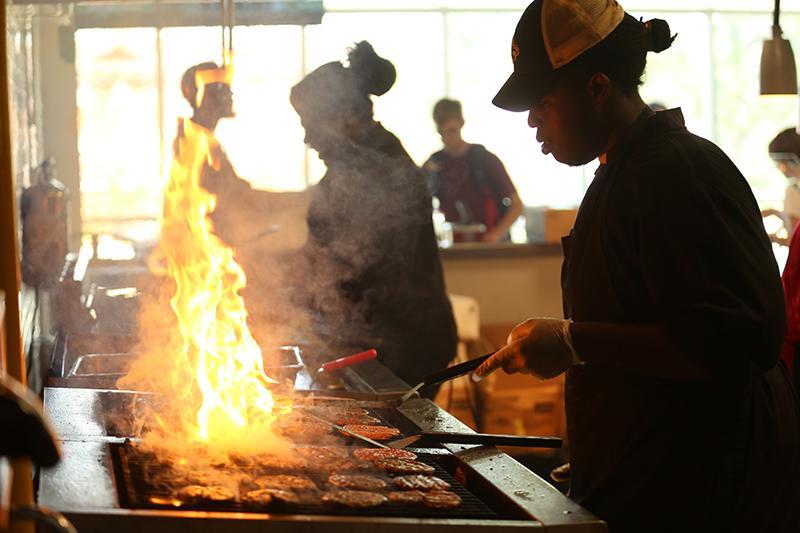UL Lafayette dining employee flips burgers on a hot grill